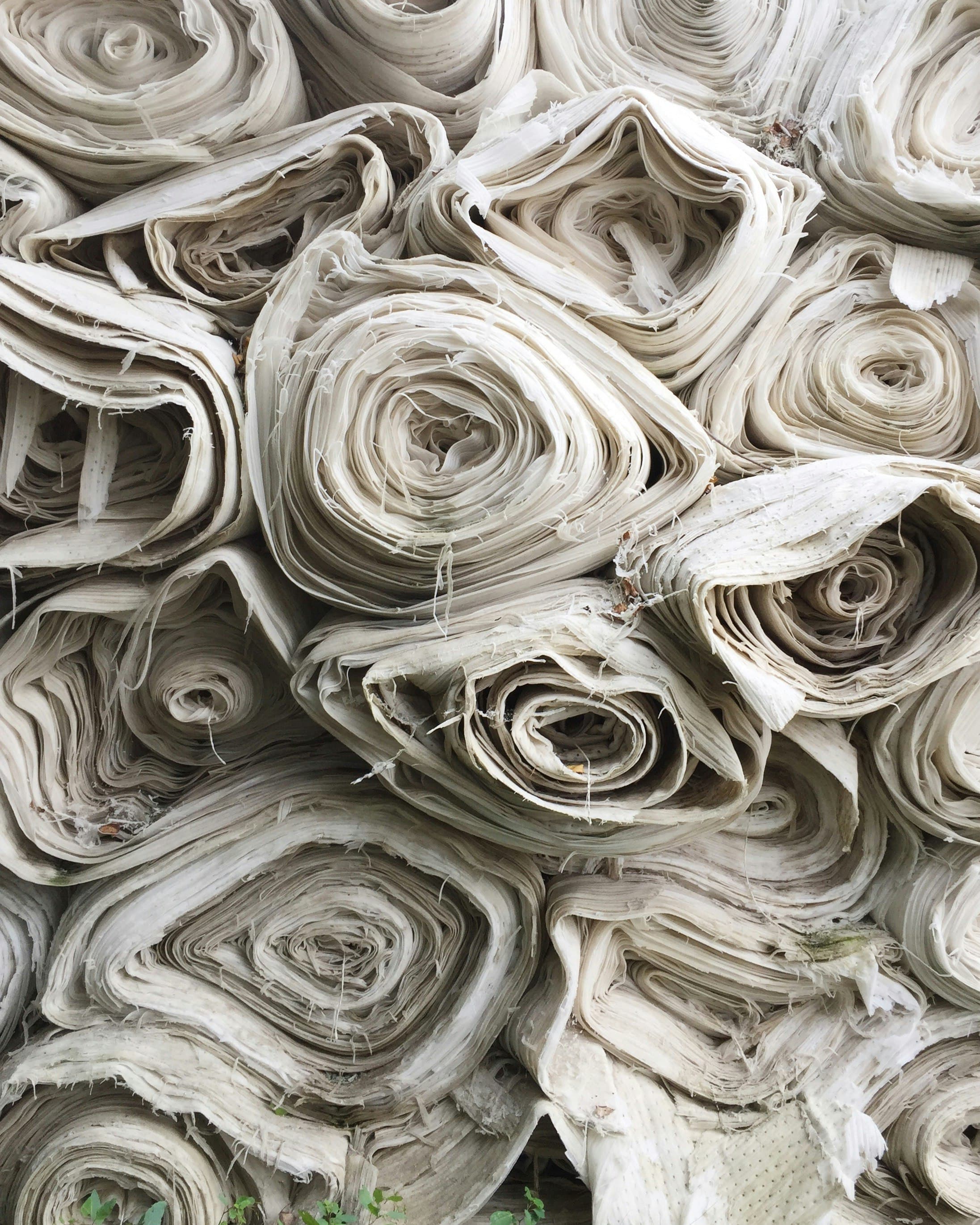 Stacked rolls of loom-state grey fabric, unbleached and untreated