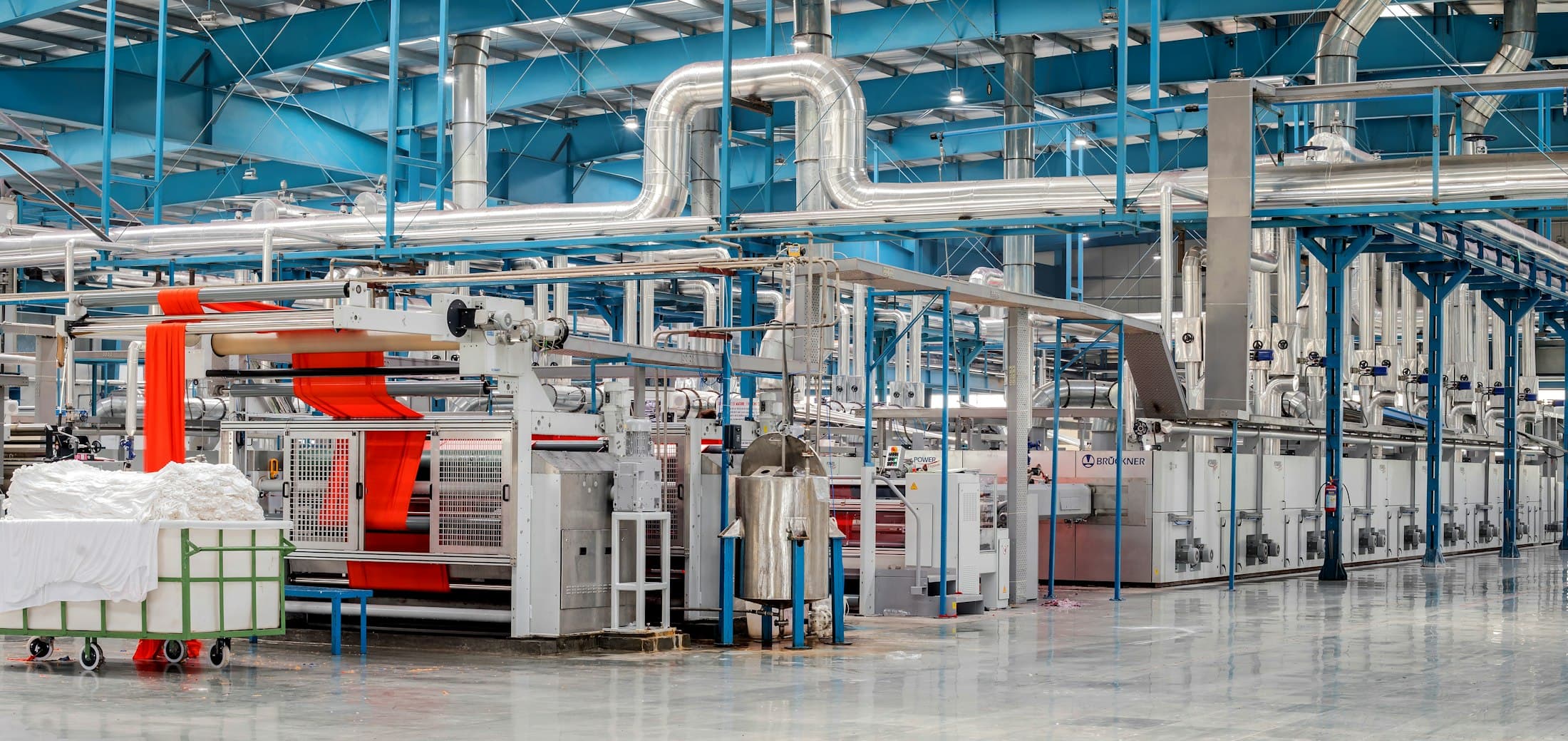 Fabric finishing line with overhead pipework running the length of the plant
